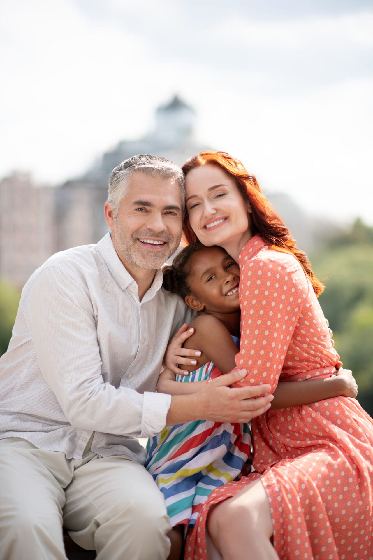 Mother and father. Foster mother and father hugging their cute happy daughter while spending day together